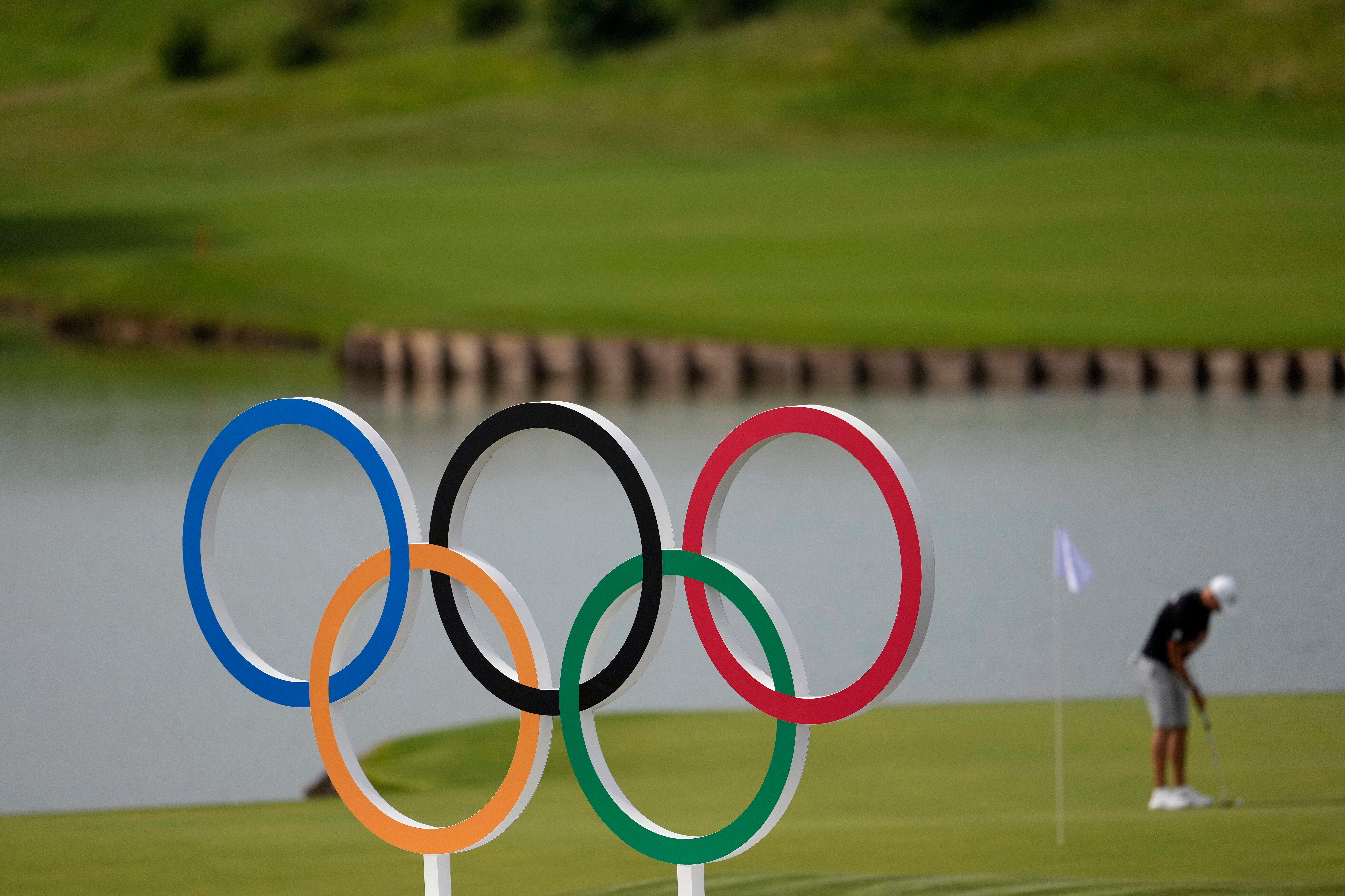 Olympic rings at Olympic golf course with golfer on putting green in the background