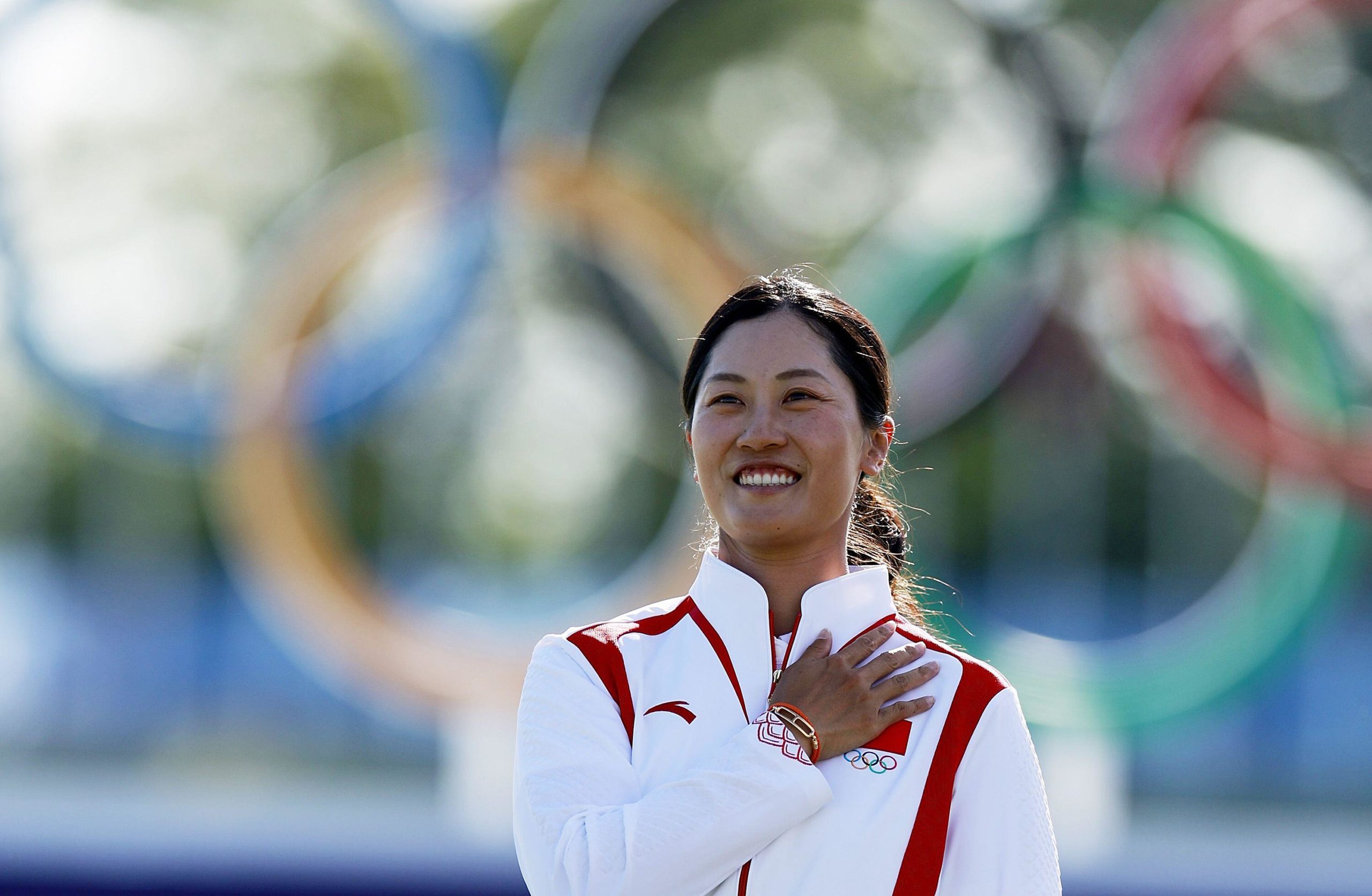 Chinese female golfer with hand on chest during national anthem ceremony at Olympics
