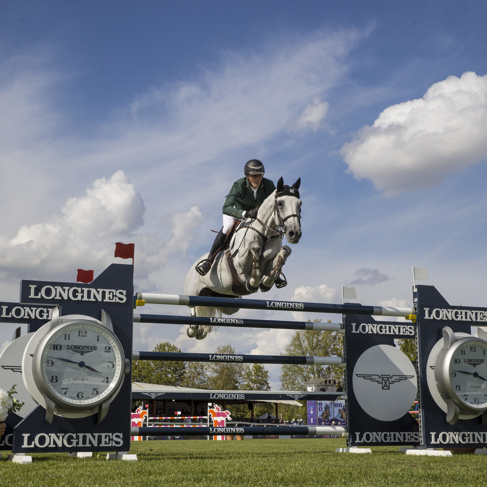 Female rider on horse jumping over Longines fence