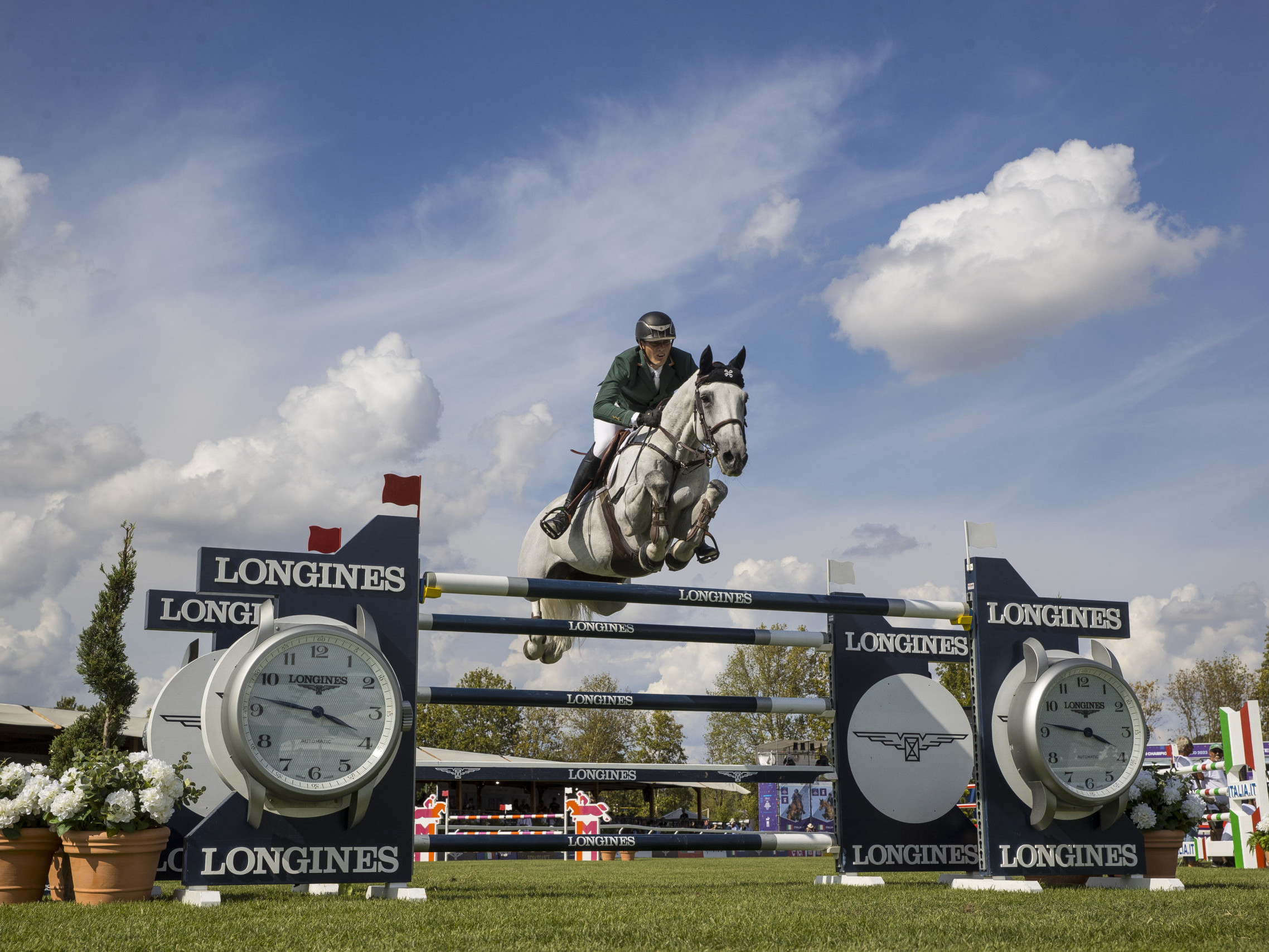 Female rider on horse jumping over Longines fence