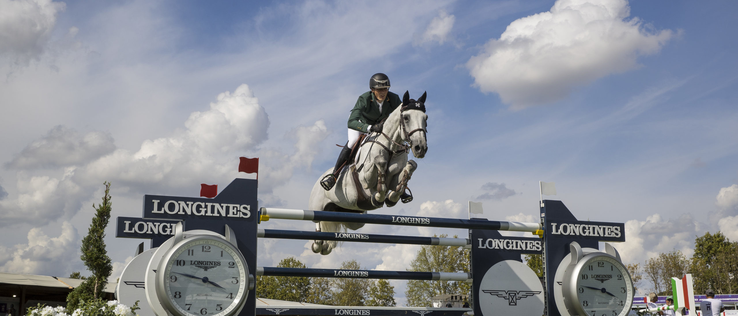 Female rider on horse jumping over Longines fence