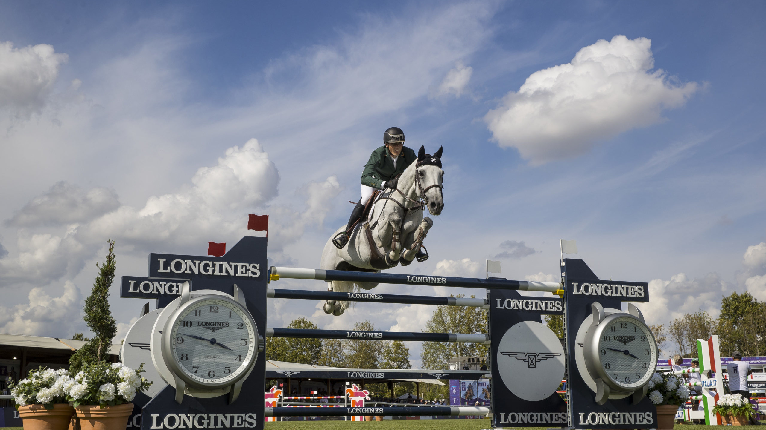 Female rider on horse jumping over Longines fence