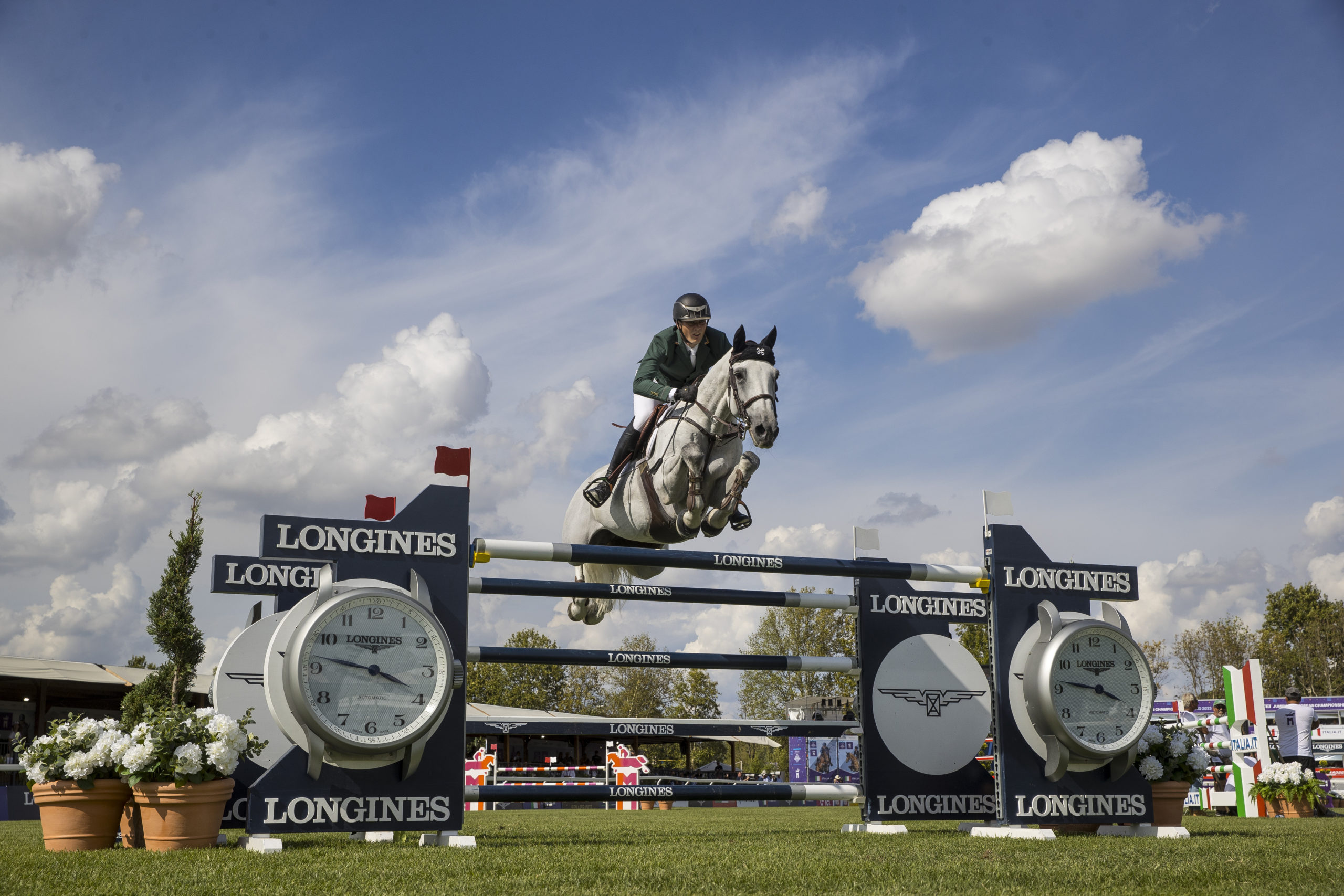 Female rider on horse jumping over Longines fence