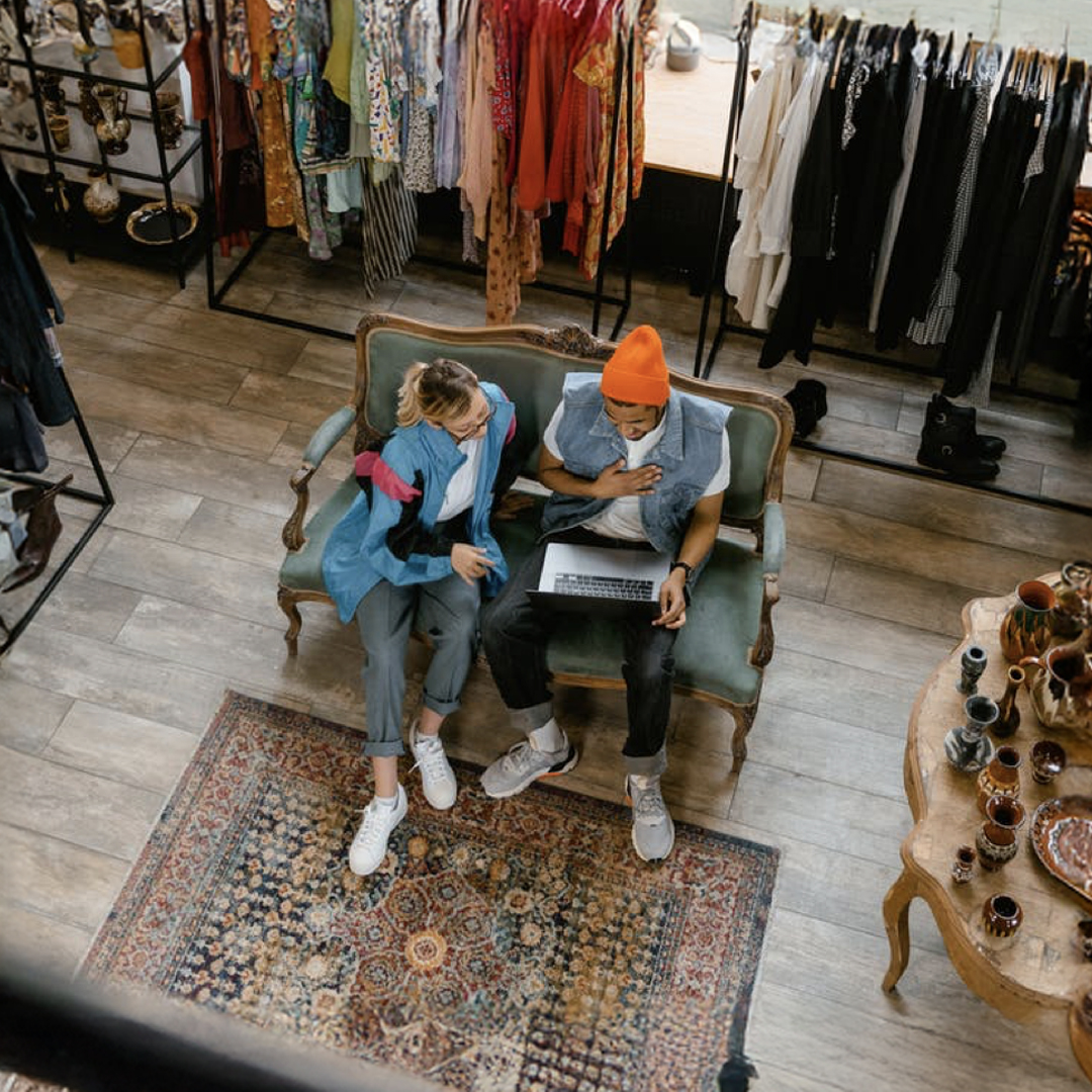 Overhead shot of two people sitting on a chair looking at a laptop screen