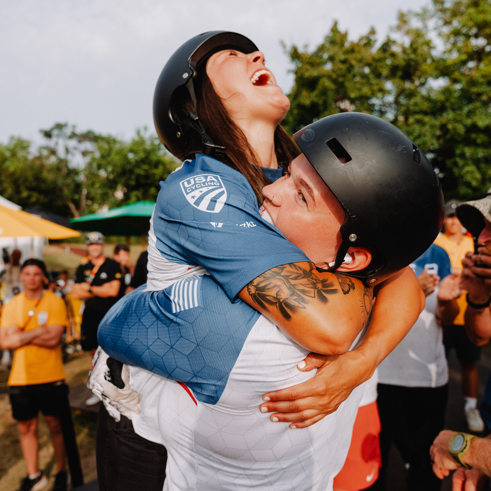 Two UCI BMX riders hugging after winning a medal.