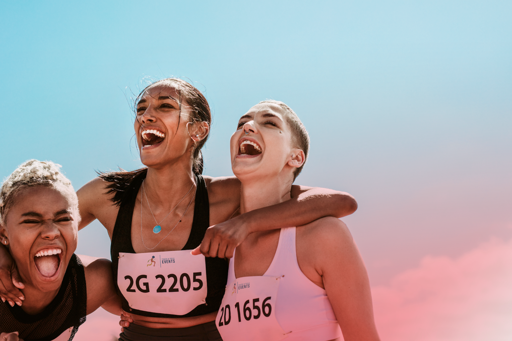 Three female runners laughing and hugging