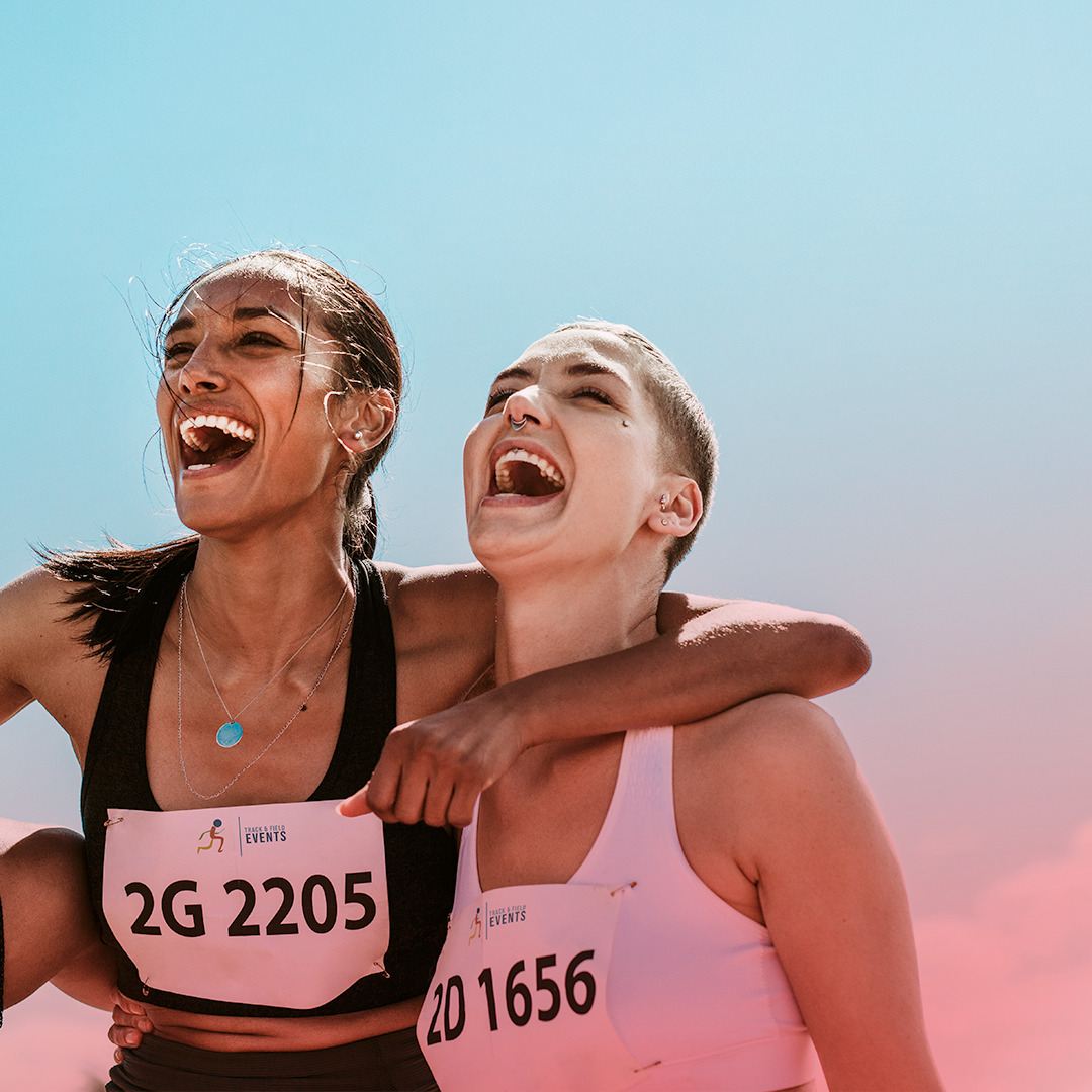 Three female runners laughing and hugging
