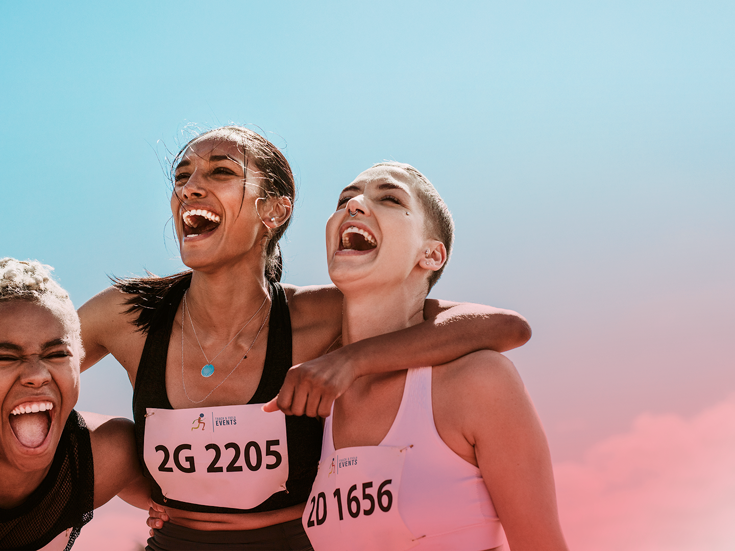 Three female runners laughing and hugging