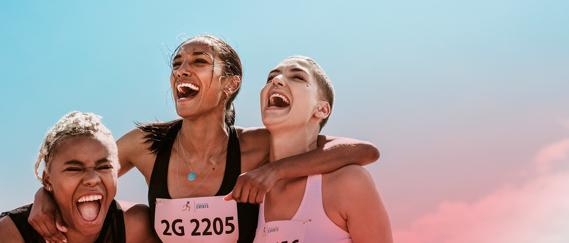 Three female runners laughing and hugging