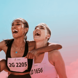 Three female runners laughing and hugging