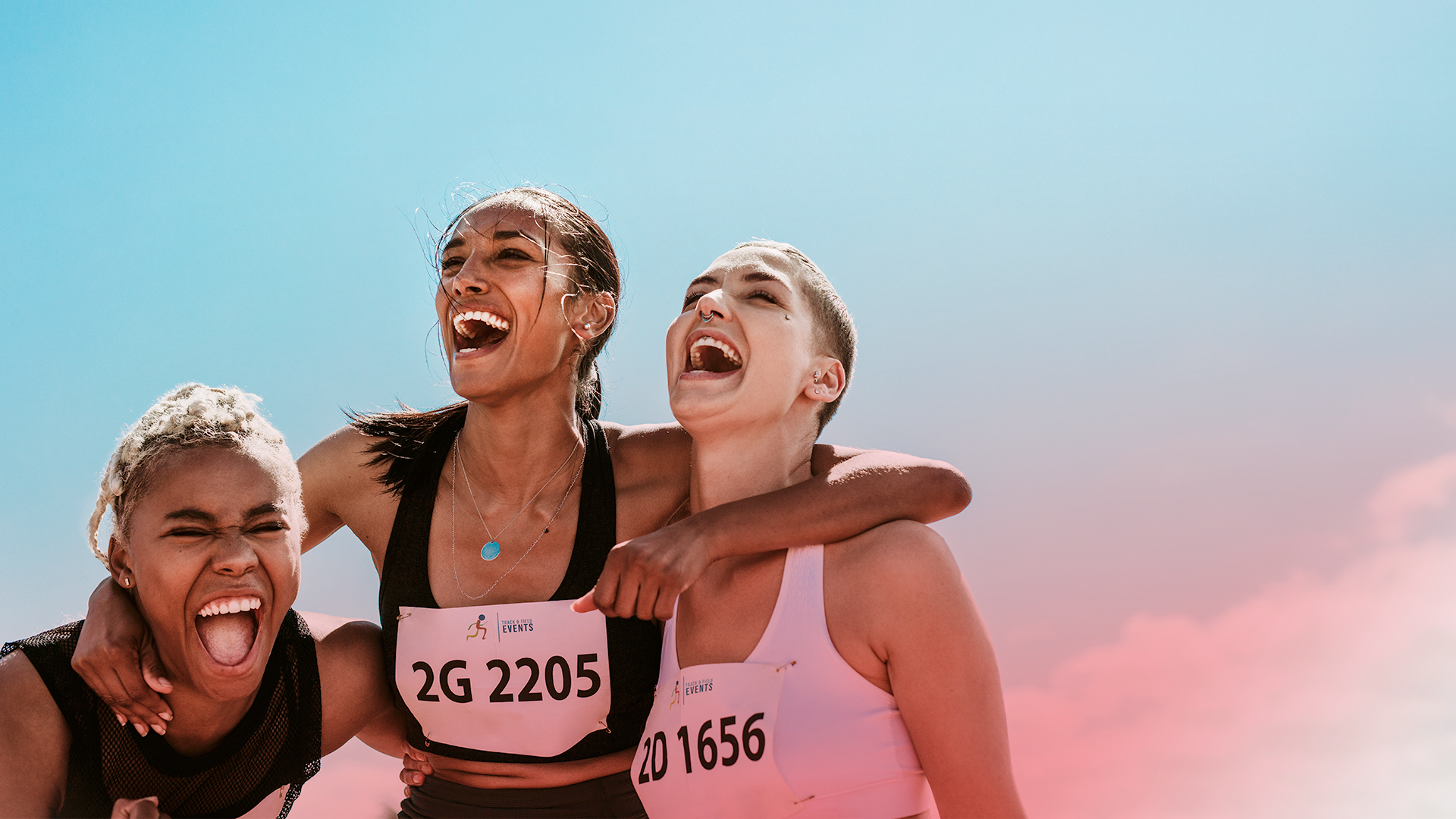 Three female runners laughing and hugging
