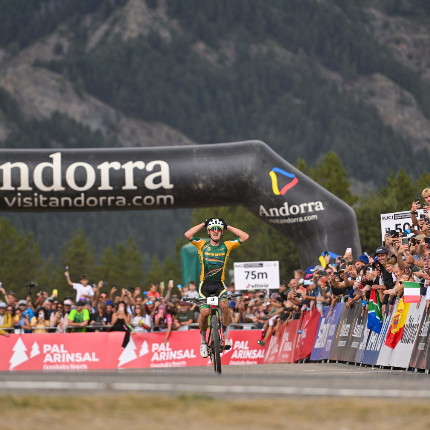 Male cyclists with hands in the air as he crosses the finish line in first
