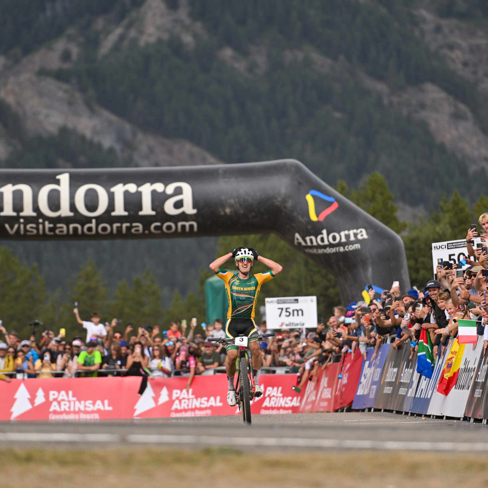 Male cyclists with hands in the air as he crosses the finish line in first