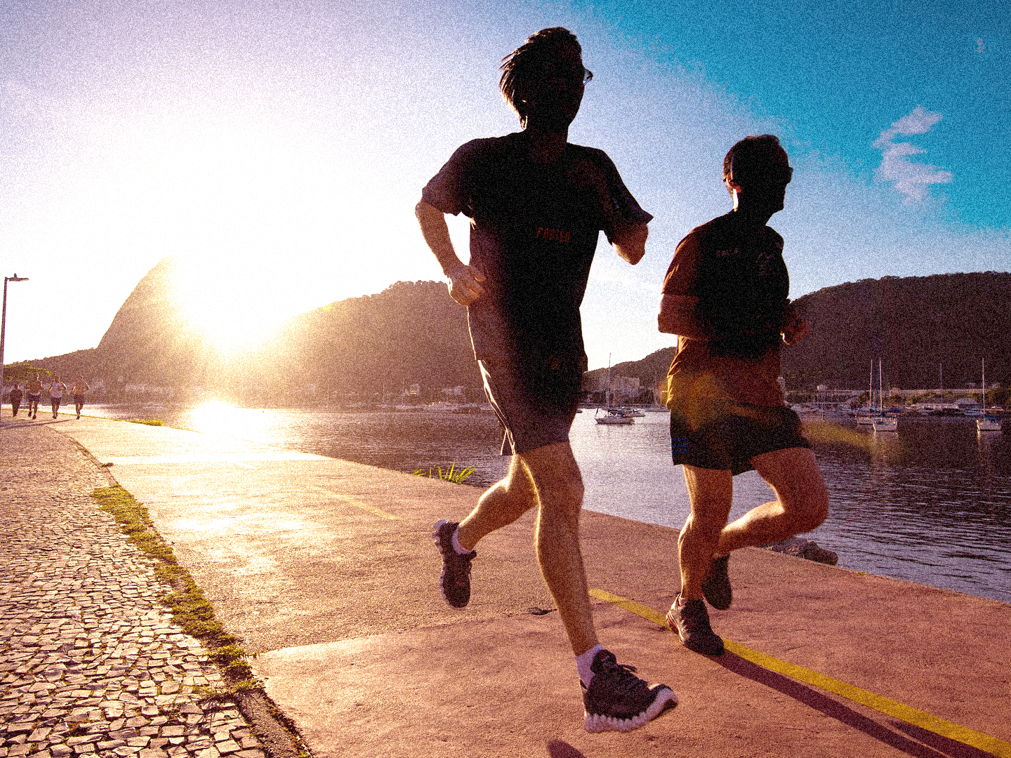 SportOnSocial Global Running Culture 2025 - Silhouette of two men running with the sun setting behind