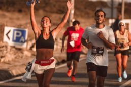 SOS Running: Two people running a race, one celebrating with her arms in the air