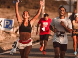 SOS Running: Two people running a race, one celebrating with her arms in the air