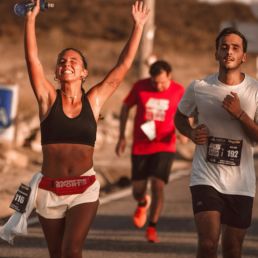 SOS Running: Two people running a race, one celebrating with her arms in the air